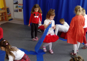 Dzieci łączą niebieskie gumy tworząc płynącą Wisłę.